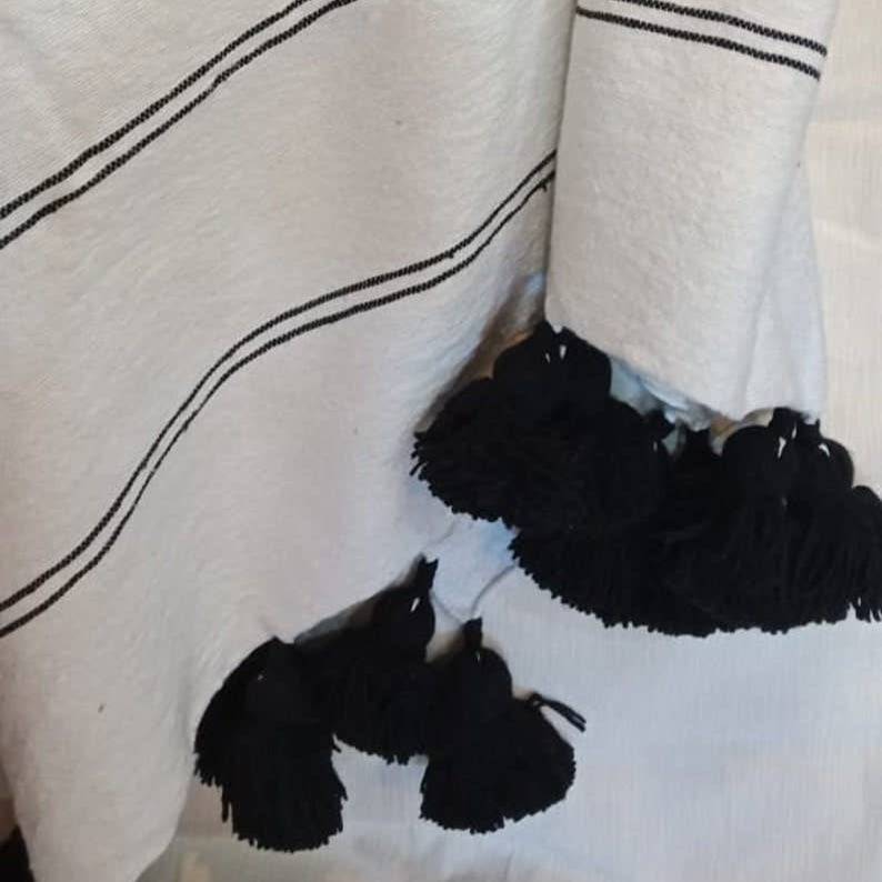 Close-up of a white fabric with black stripes and tassels.