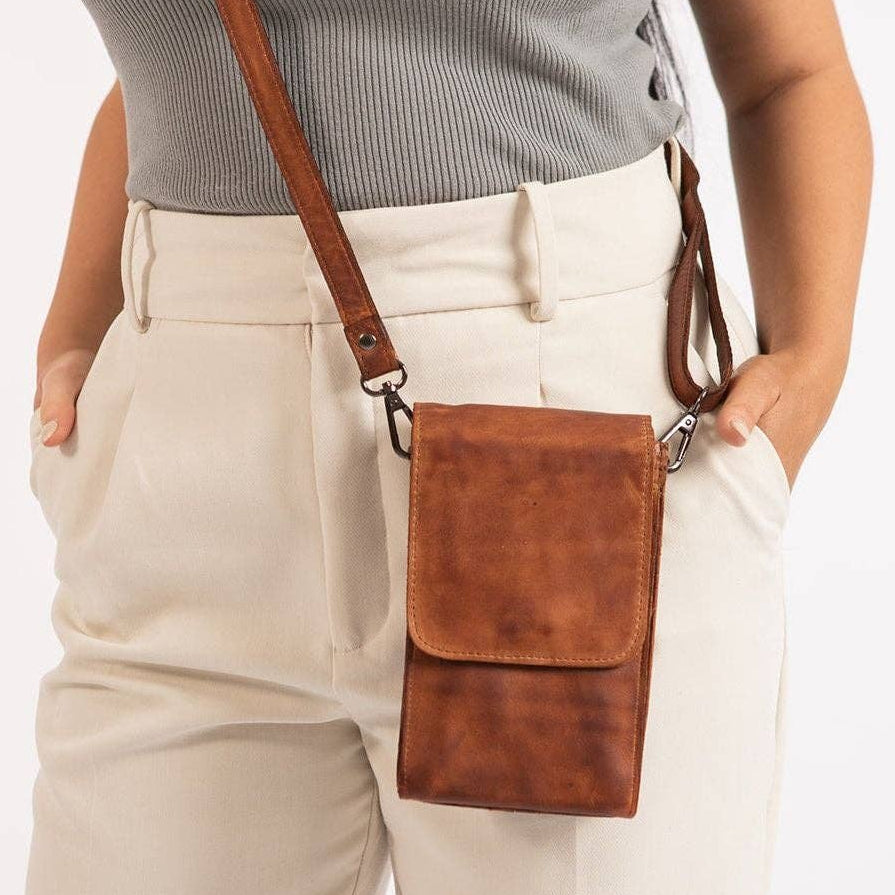 Person wearing beige pants and a brown crossbody bag on a white background