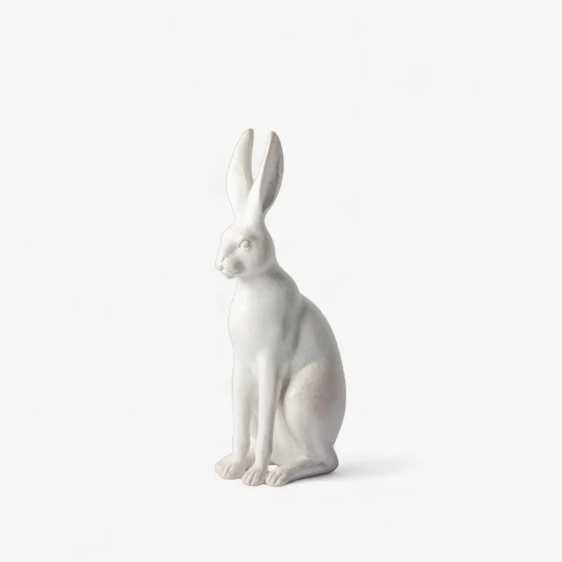 A white ceramic rabbit figurine in a sitting position, shown against a plain white background.