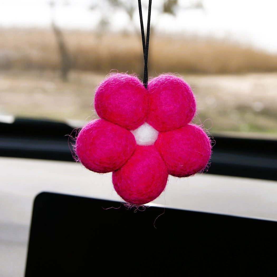 Pink flower-shaped car air freshener hanging in a car.