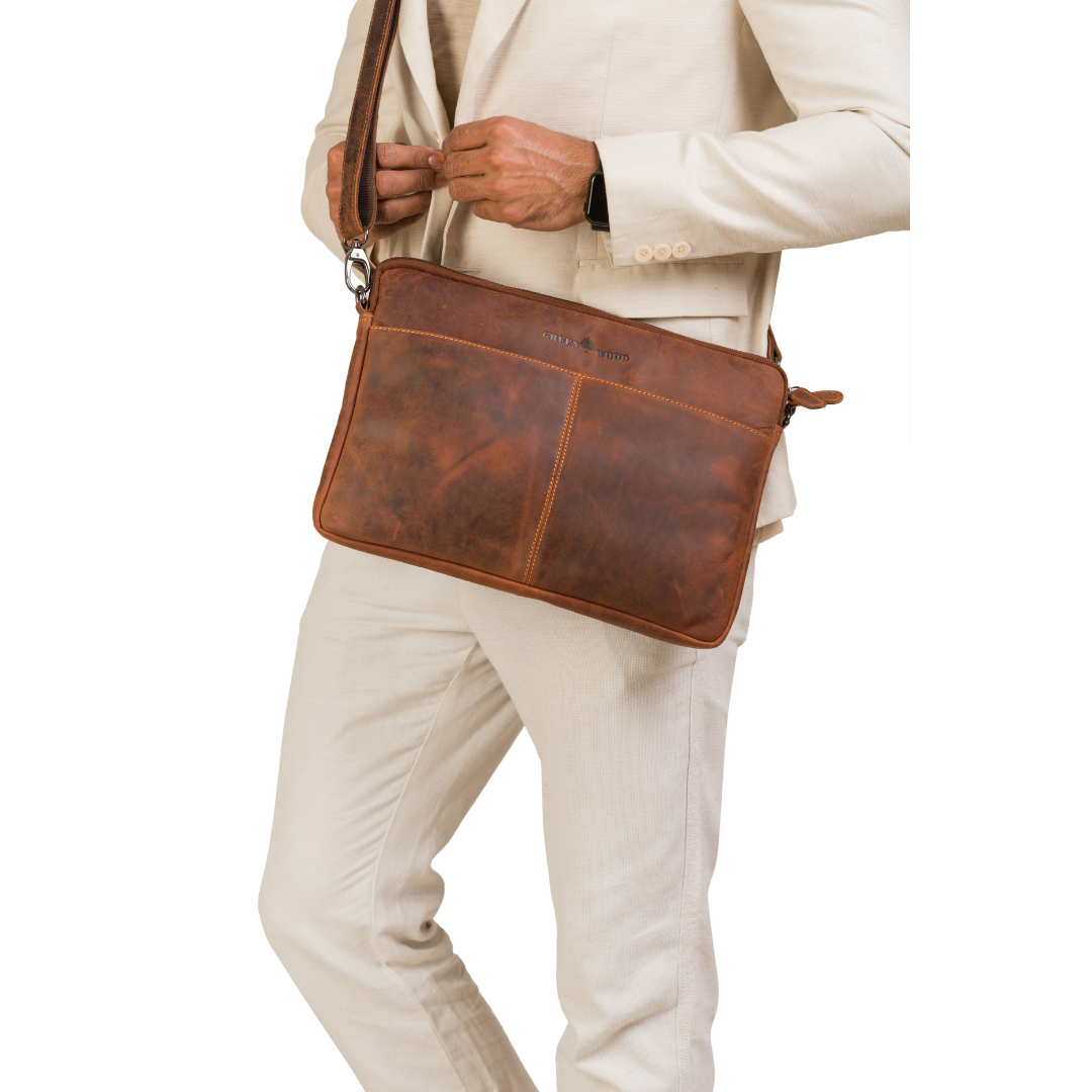 Brown leather bag worn over shoulder by a person in a beige suit on a white background