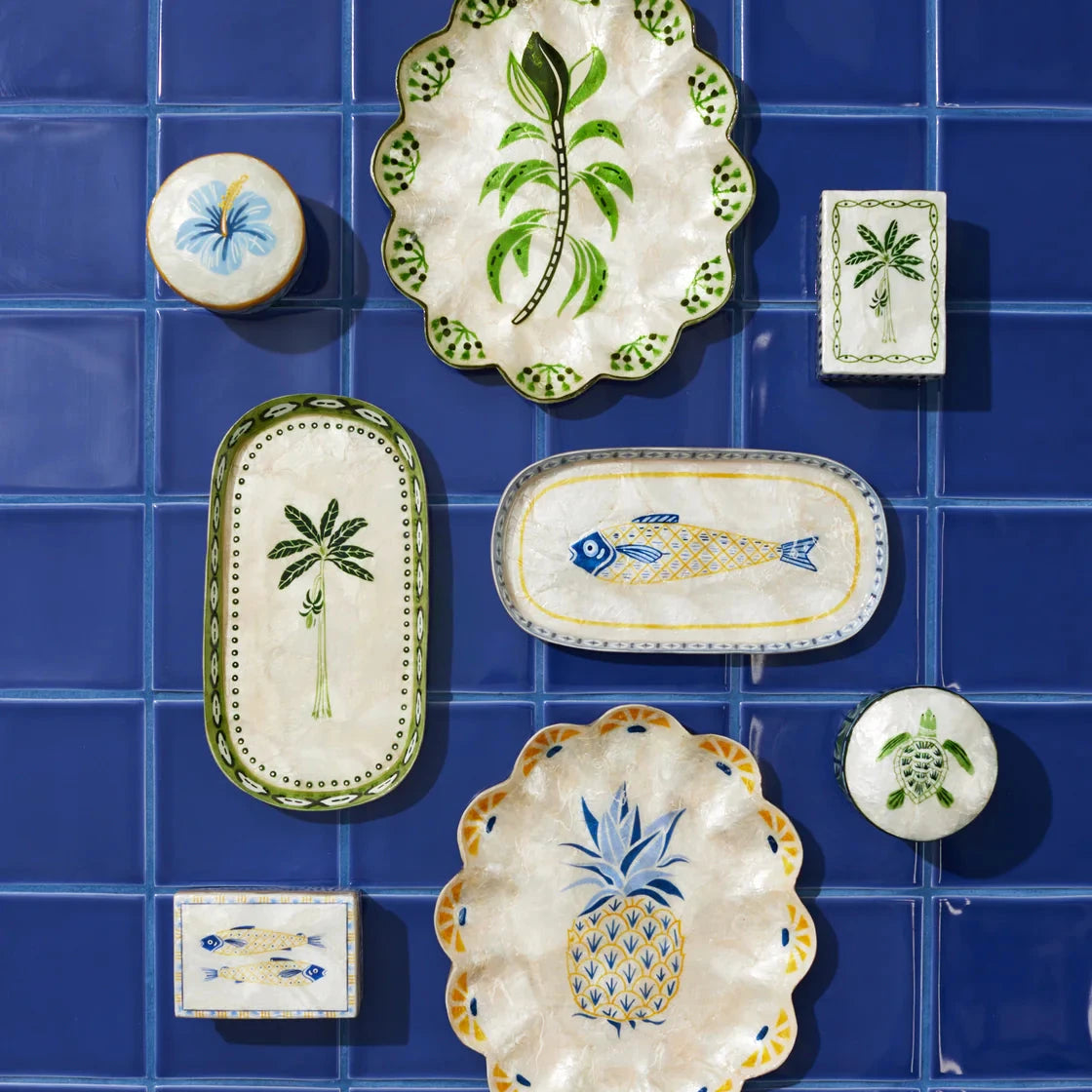 Collection of decorative ceramic plates with various designs on a blue tiled background