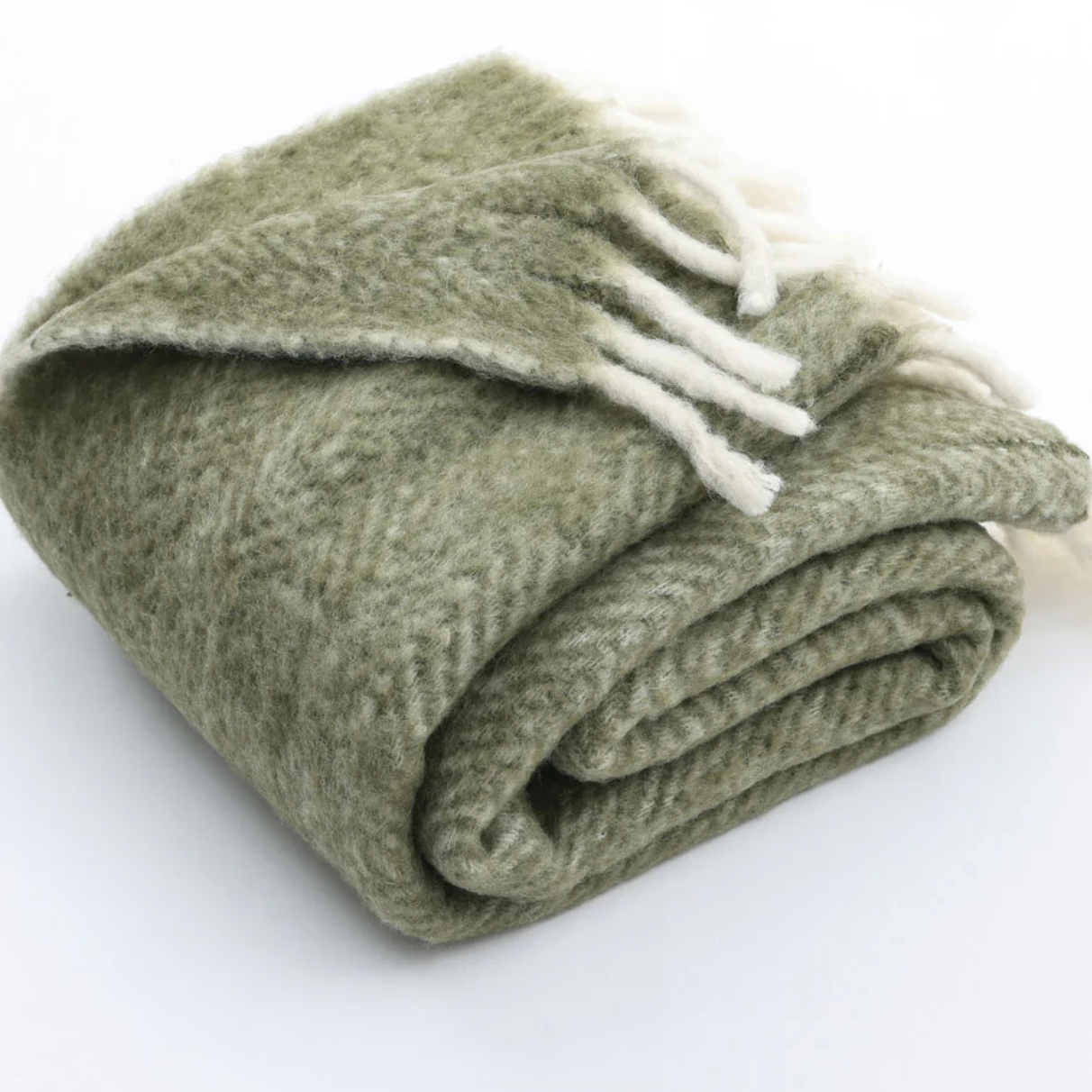 Folded green blanket with white tassels on a white background