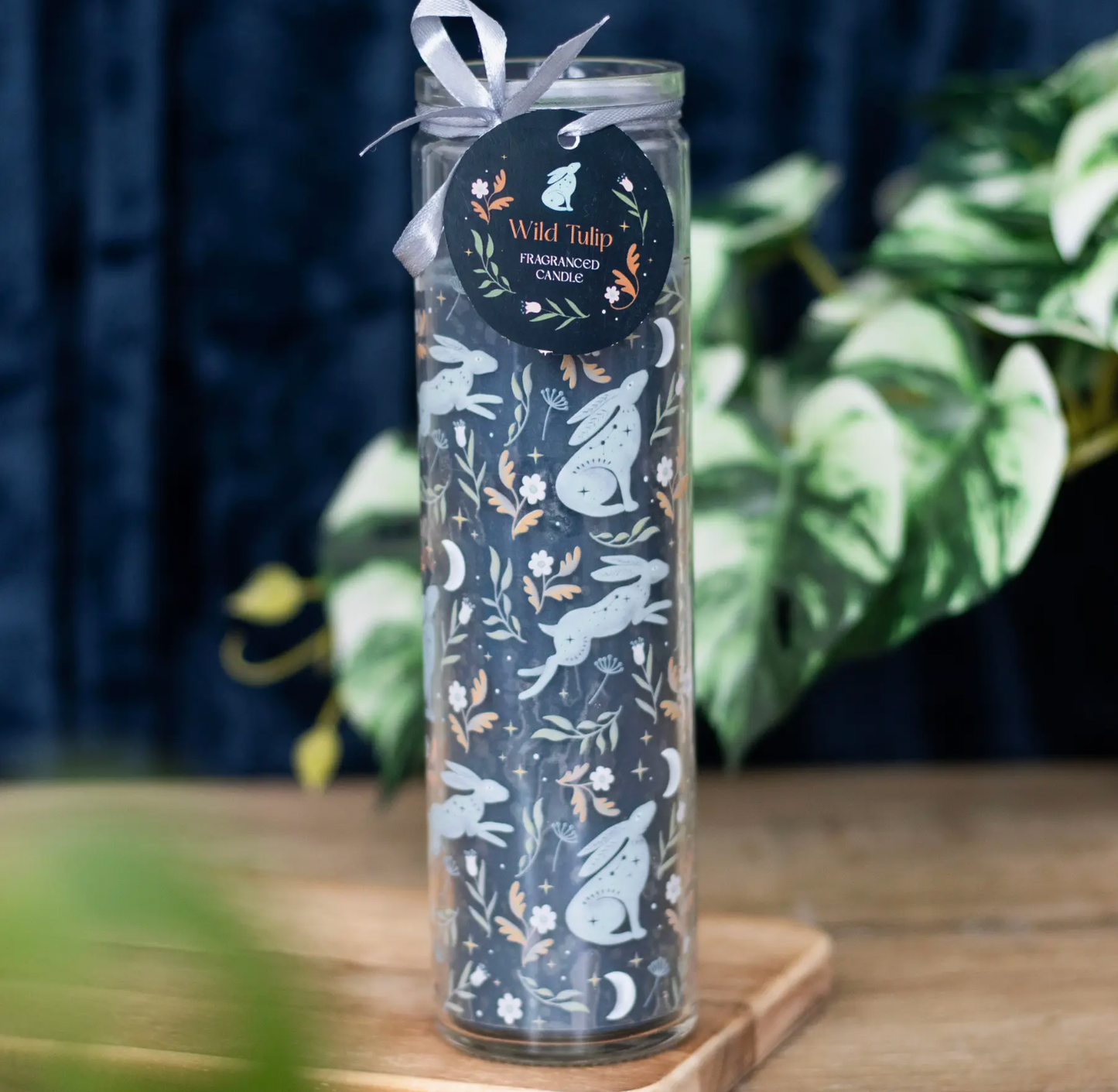 Decorative candle with rabbit and floral design on a wooden surface