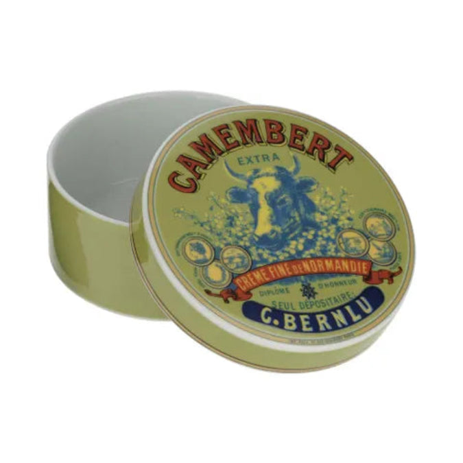 A round green ceramic bowl with its lid leaning against the base. The lid features a vintage-style illustration of a cow and French text.