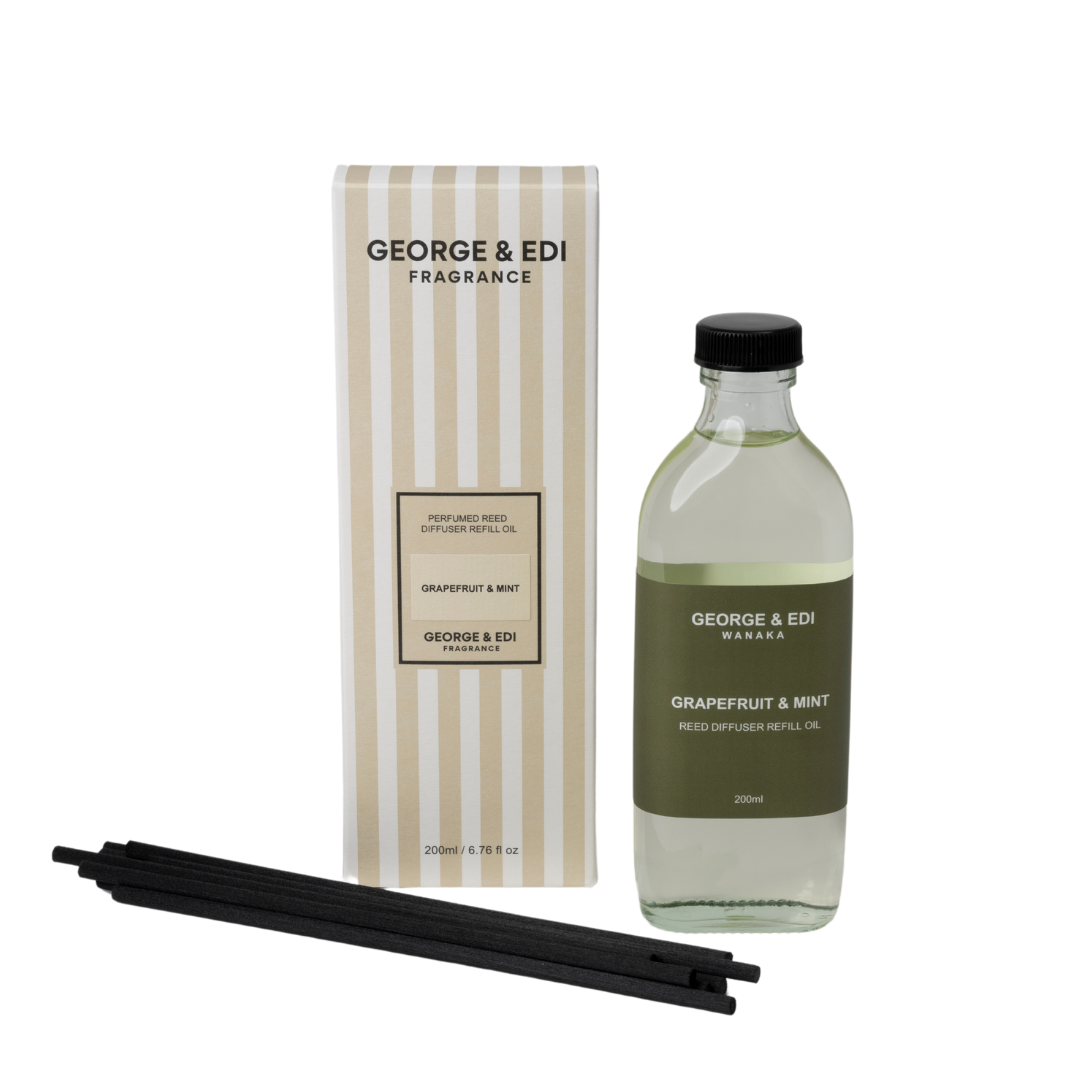 George & Edi fragrance set with bottle, packaging, and reeds on a white background