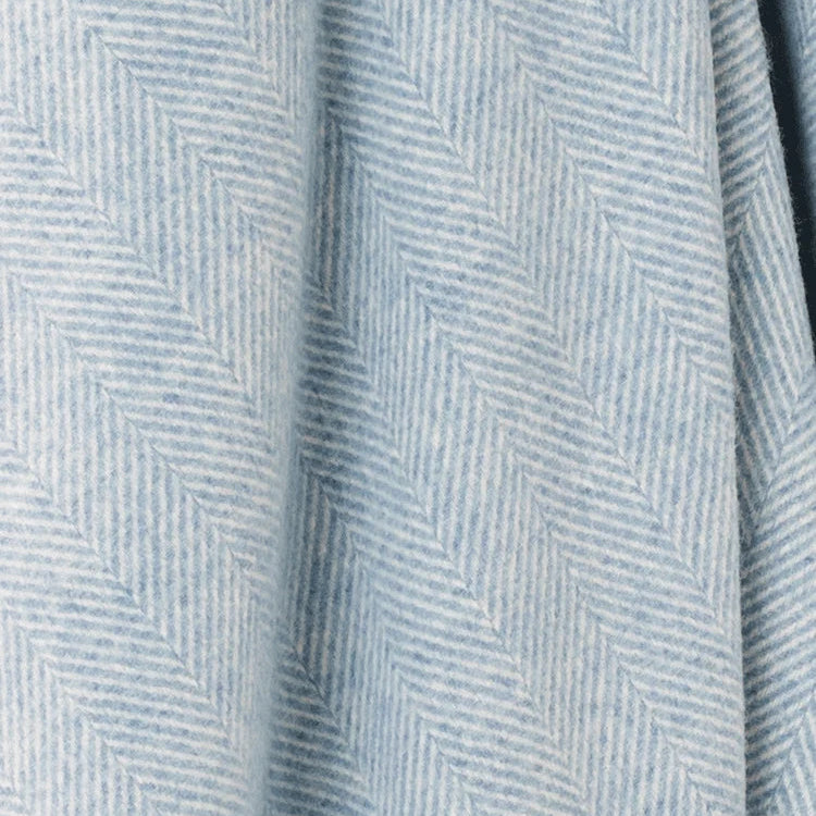 A close-up of a light blue and white herringbone patterned fabric with soft folds.
