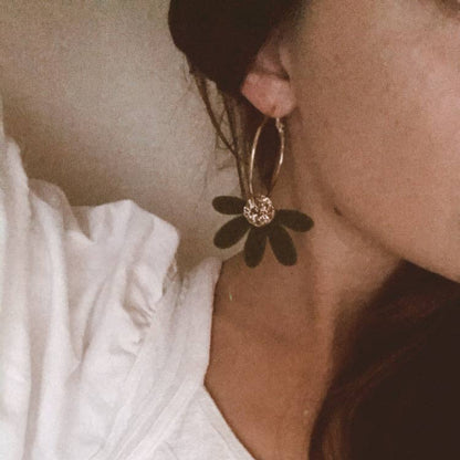 Close-up of a person wearing a white dress with floral earrings.