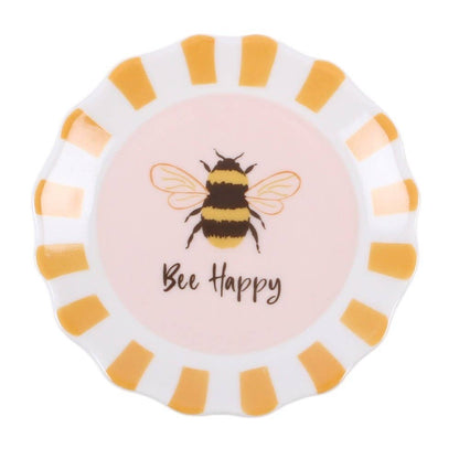 A round decorative plate with a scalloped edge, featuring a light pink center printed with a bumblebee and the words 'Bee Happy', surrounded by alternating white and yellow stripes.