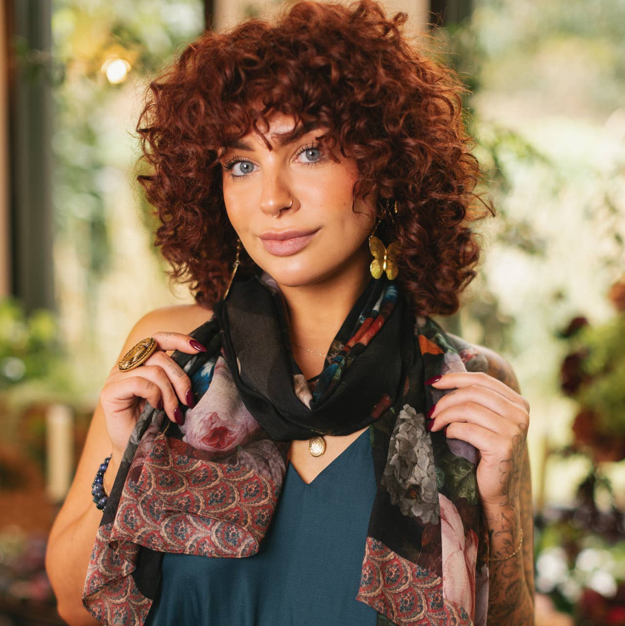 Woman with curly hair wearing a patterned scarf in an outdoor setting