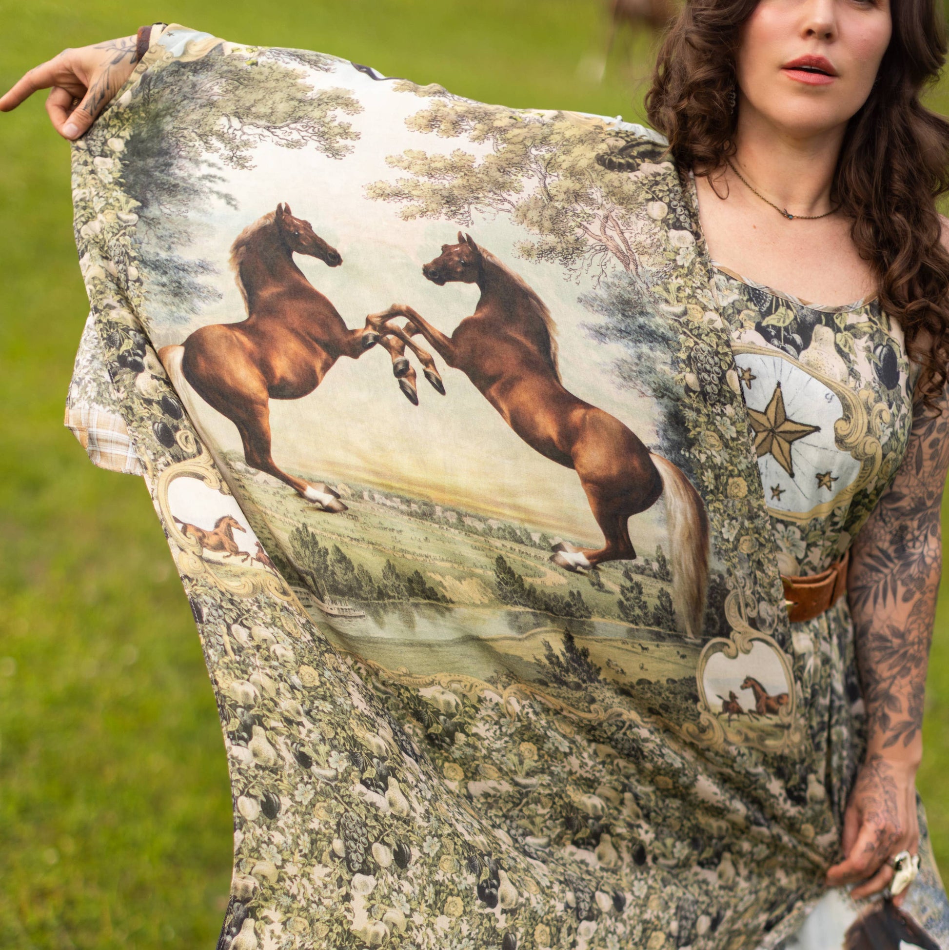 Person holding a dress with horse print in an outdoor setting