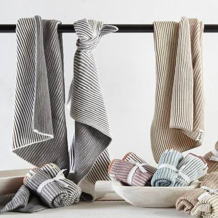 Set of folded striped towels in various colors on a towel rack with a bowl of additional towels below.