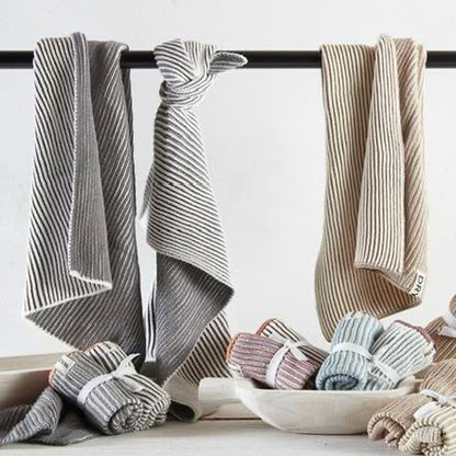 Set of folded striped towels in various colors on a towel rack with a bowl of additional towels below.