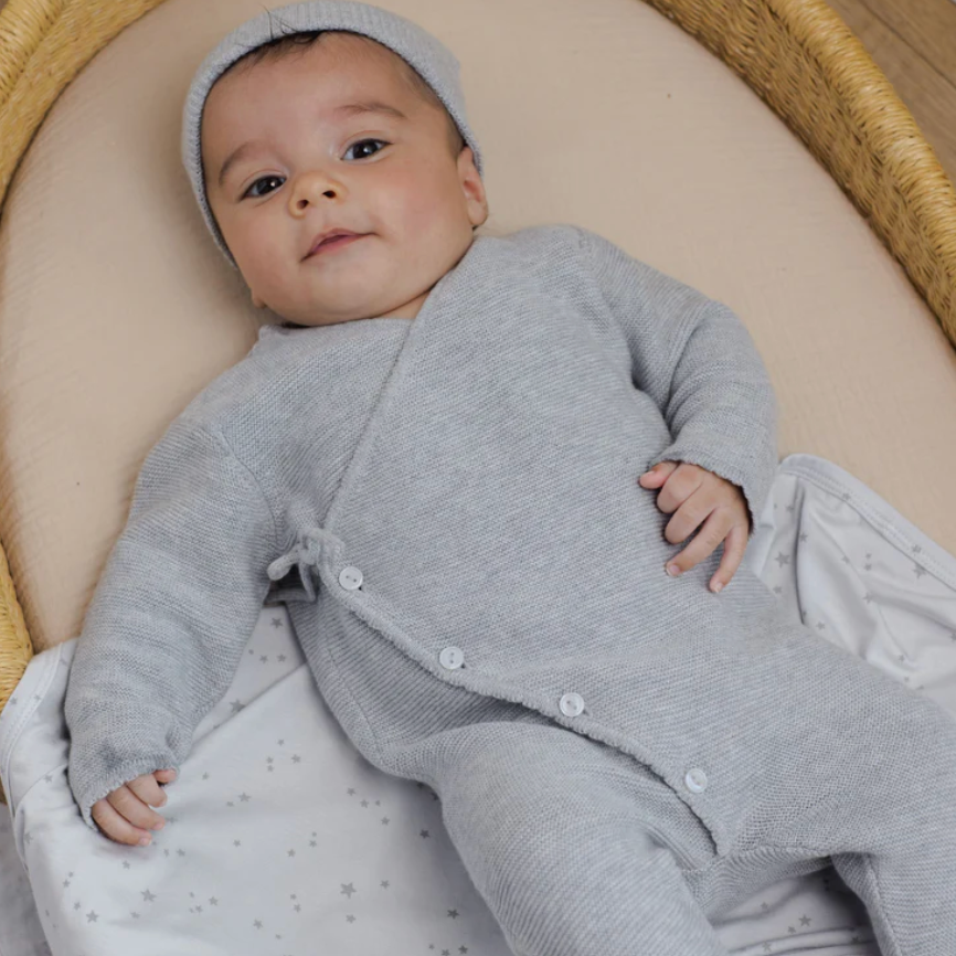 Baby in a gray outfit lying on a soft surface