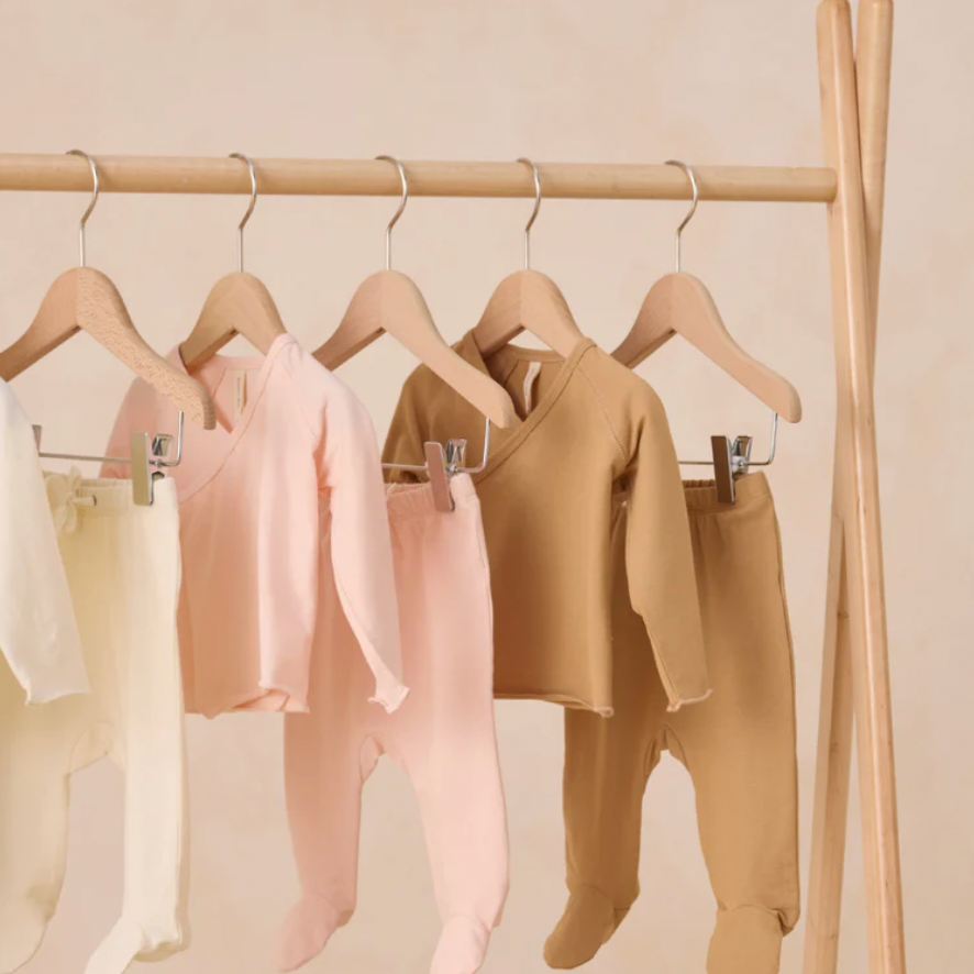 Children's clothing on hangers against a beige wall