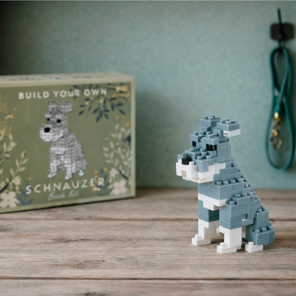Toy dog made of interlocking bricks in front of a box labeled 'Build Your Own Schnauzer'.