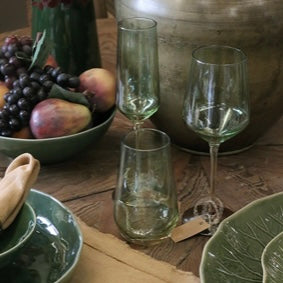 Capri Green glassware on a rustic wooden table with fruits and a large container.
