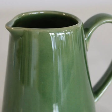 Close up Green ceramic creamer on a plain background