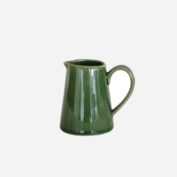 Green ceramic creamer on a white background