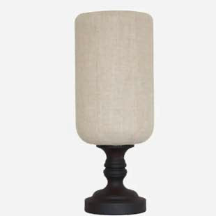 Table lamp with a beige fabric shade and black base on a white background