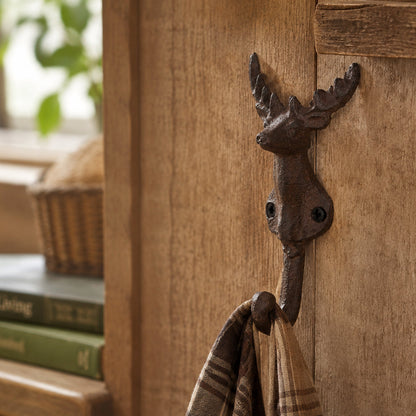 A dark cast iron deer hook mounted to a wooden wall.