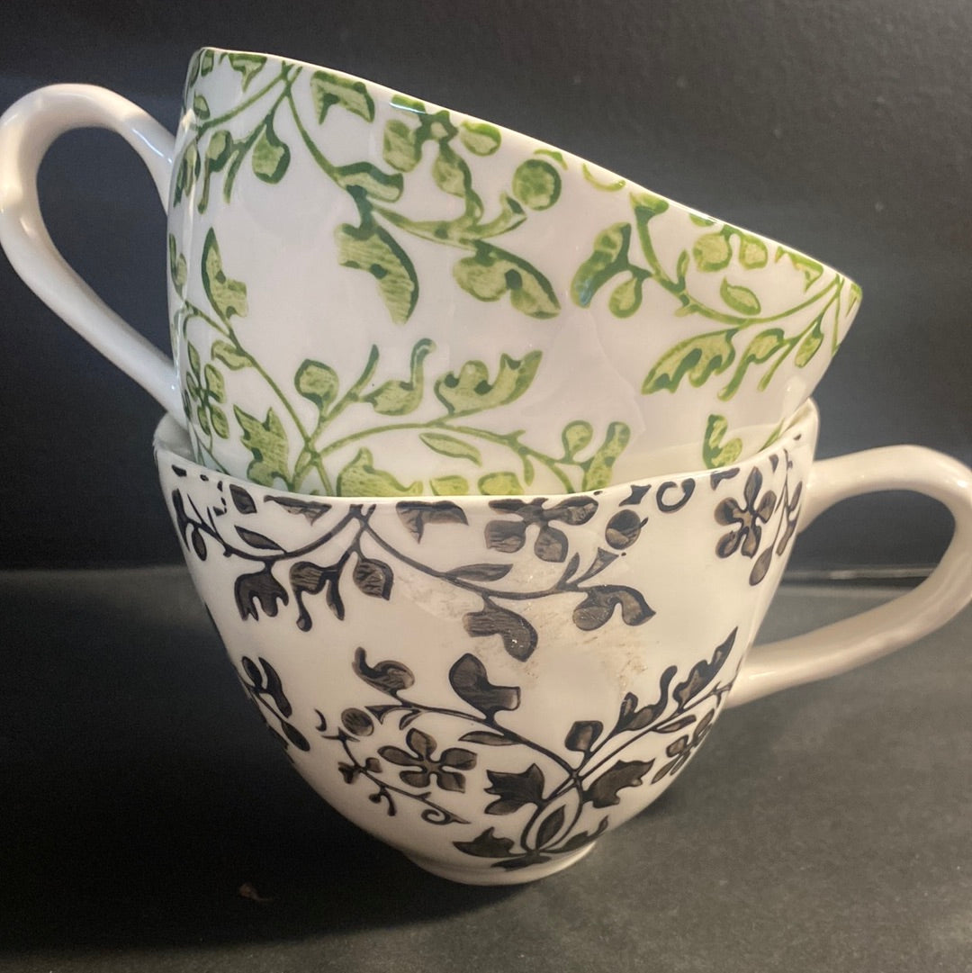 Two hand-painted Florentine cups, one with a green floral pattern and the other with a black floral pattern, both on a white background.
