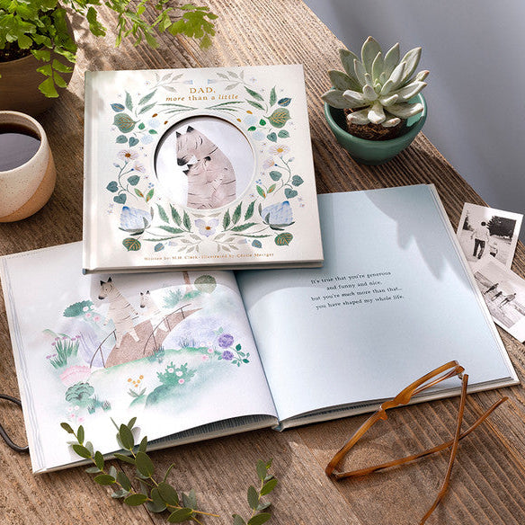 Children's book with illustrations on a wooden table with plants and a mug.
