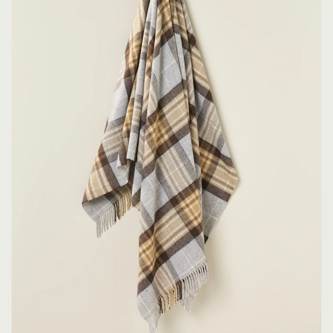 Plaid blanket with brown, beige, and gray colors on a beige background