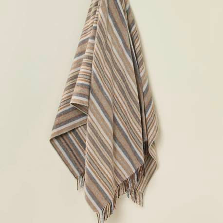 Striped throw with fringes on a light beige background
