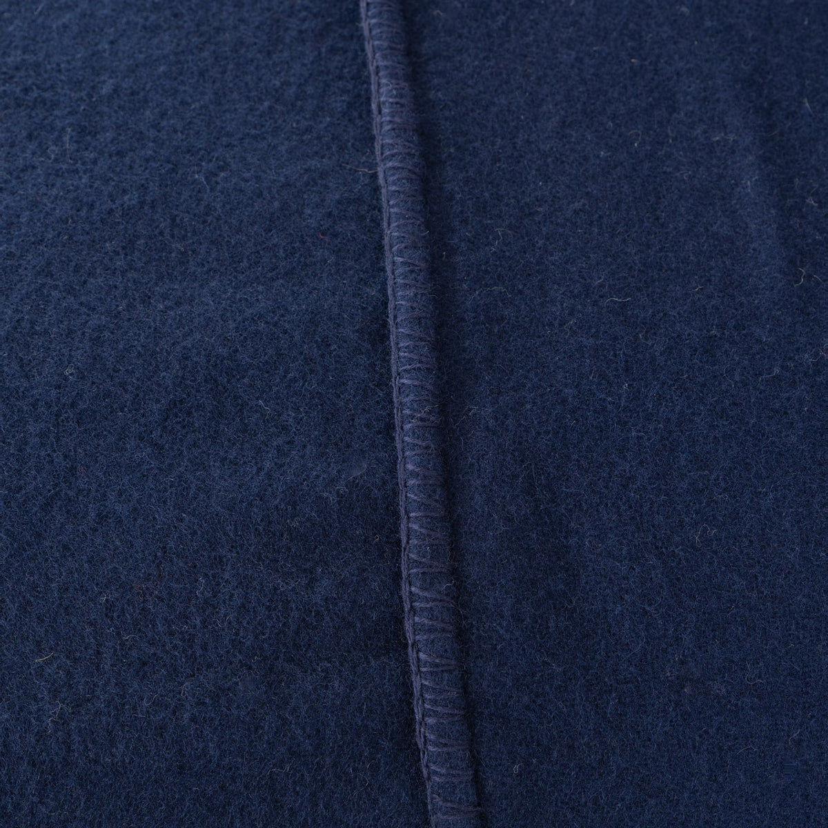 Close-up of a dark navy blue textured fabric with a vertical stitched seam.