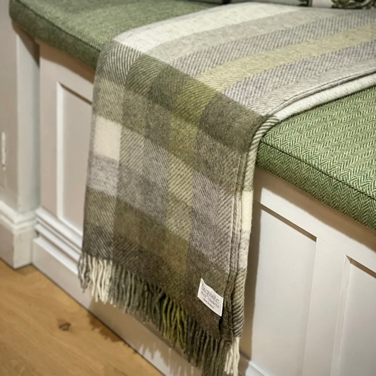 Plaid blanket draped over a bench with a visible brand label.