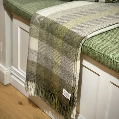 Plaid blanket draped over a bench with a visible brand label.