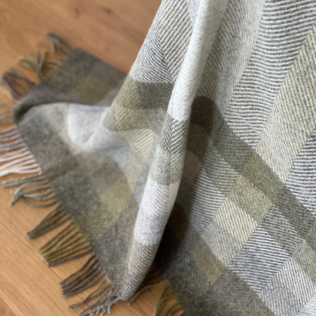 Plaid blanket with fringe on a wooden surface