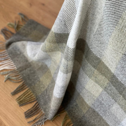 Plaid blanket with fringe on a wooden surface