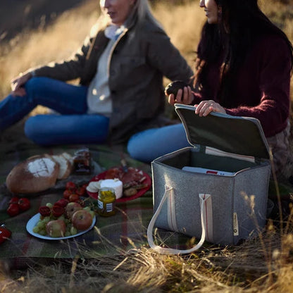 Two people having a picnic in a field with a cooler box.