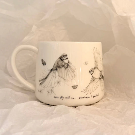 White mug with bird illustrations and text on a soft white background