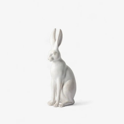 A white ceramic rabbit figurine in a sitting position, shown against a plain white background.