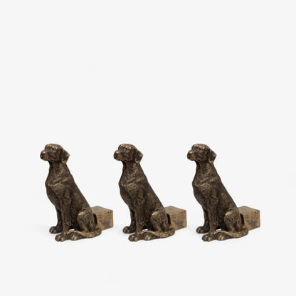 Three bronze dog figurines on a light gray background