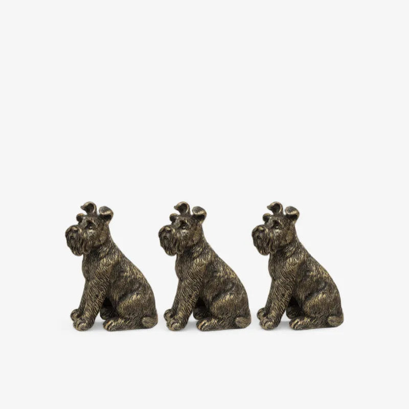 Three bronze dog figurines sitting side by side on a white background