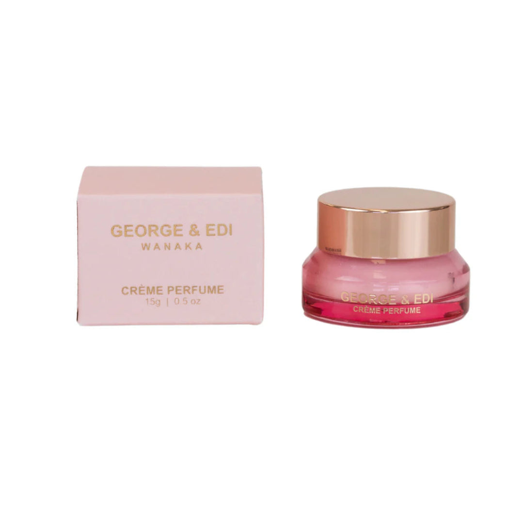 Pink crème perfume jar with gold cap and matching box on a white background