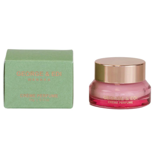 Pink crème perfume jar with gold cap and matching box on a white background