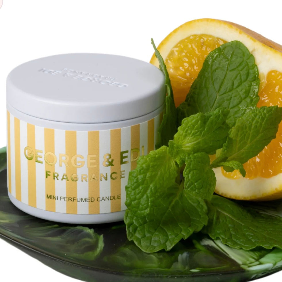 Candle jar with 'George & El' branding next to a lemon and mint leaf on a white background