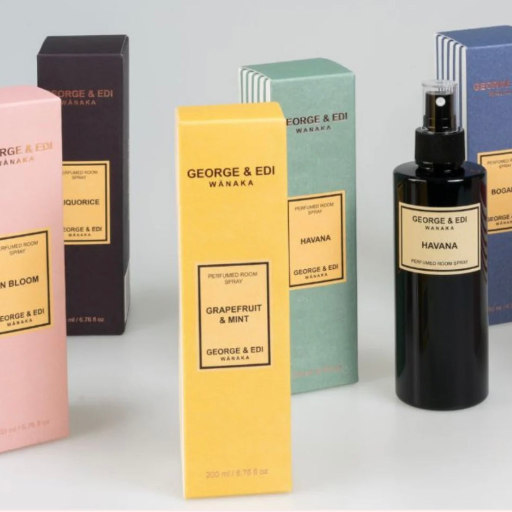 Collection of George & Edi waxaka products including boxes and a bottle on a light gray background