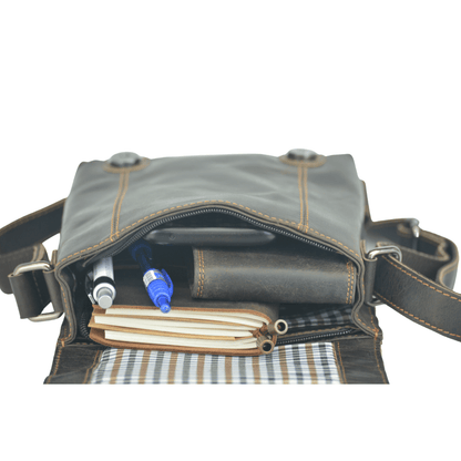 Brown leather bag with pen and notebook on a white background