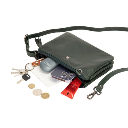 Green crossbody bag with items like keys, phone, and lip balm displayed on a white background
