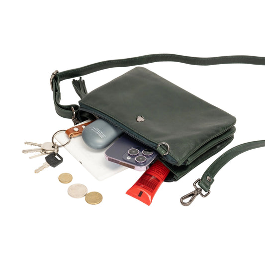Green crossbody bag with items like keys, phone, and lip balm displayed on a white background