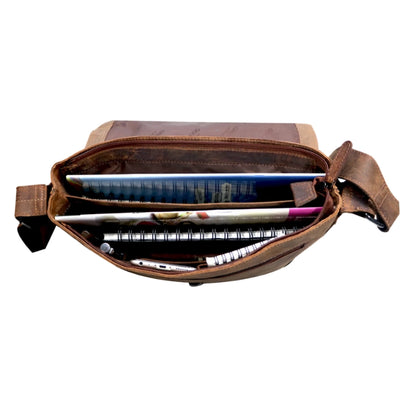 Brown leather crossbody bag with items inside on a white background