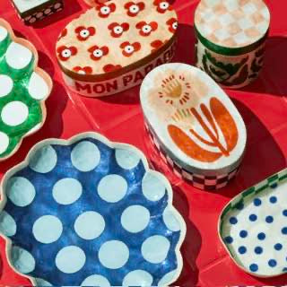 Collection of colorful ceramic dishes with various patterns on a red surface