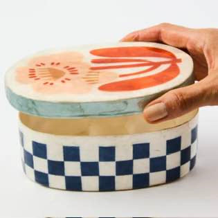 Hand holding a ceramic container with a watermelon design on a white background
