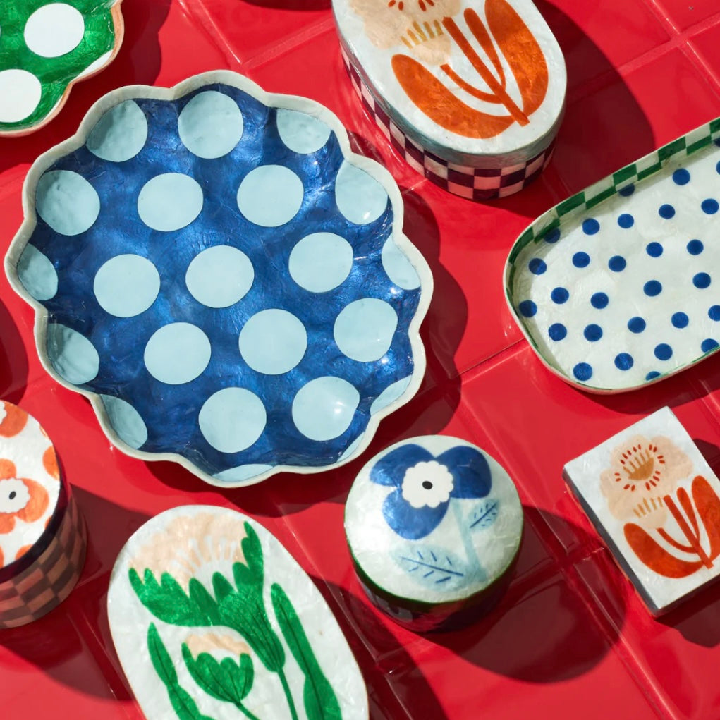 Collection of ceramic plates with polka dots and floral designs on a red surface